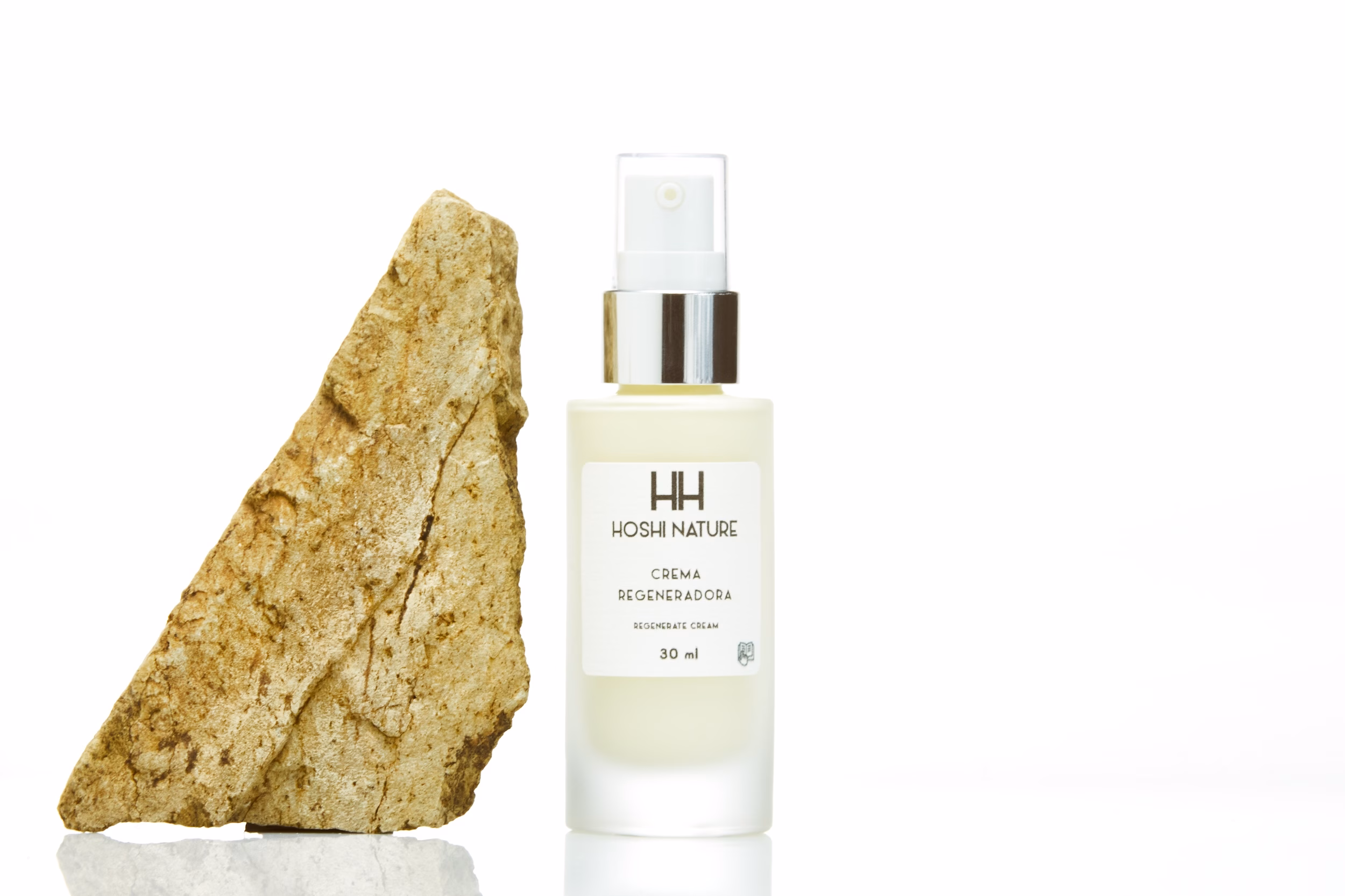 bote de crema regeneradora de Hoshi Nature al lado de una piedra